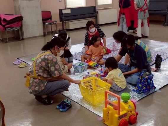 3人の子どもを、3人の民生委員と2人の中学生が面倒を見る様子。