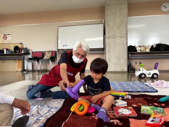 おもちゃを持っている子どもと遊ぶ民生委員