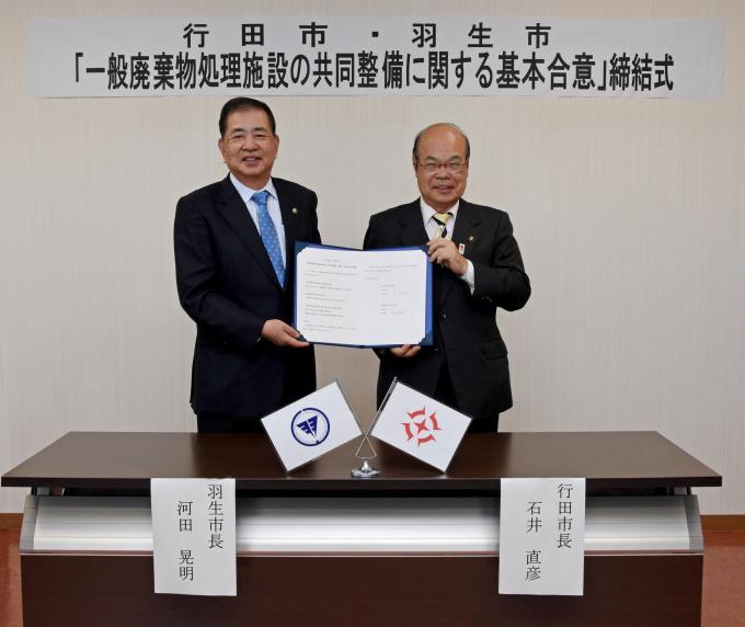 行田市長と羽生市長が締結書を2人で持って笑顔で並んで写っている締結式の写真