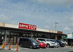 「生鮮市場TOP」と書かれた赤い色の看板がある行田店の店舗外観写真