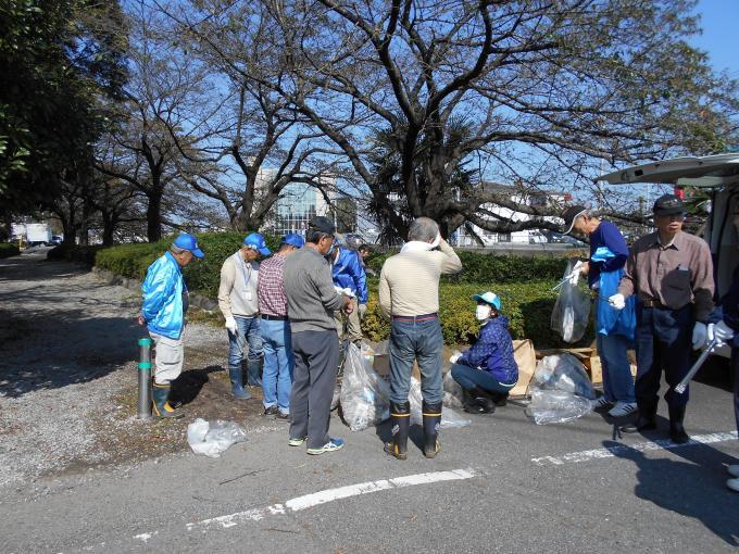 回収したごみが入ったごみ袋や火ばさみをもって集まって話をしている清掃活動の参加者の写真