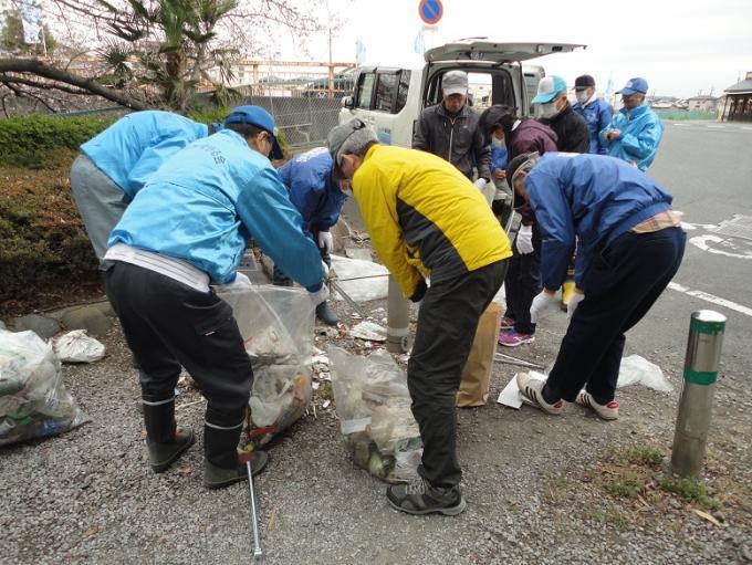 川の清掃活動で回収したごみを集めて分別している参加者の写真