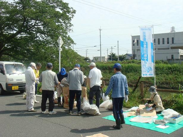 忍川・吾妻橋付近で拾ったごみを集める参加者とグリーンシートに座ってごみ袋を広げて作業をしている参加者の写真