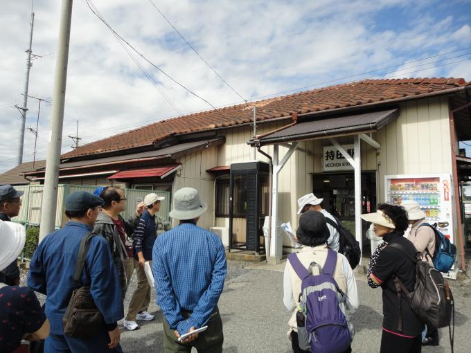 木造で白色の壁、赤っぽい屋根の持田駅の前に集まっている参加者の方々の写真