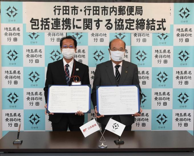 包括連携に関する協定の書類を持った、行田郵便局金子局長と石井市長の記念写真