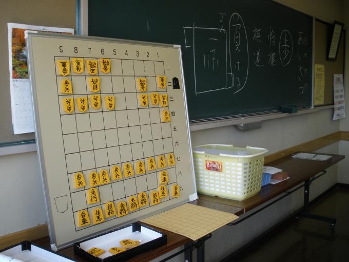 碁盤の目が書かれたホワイトボードに将棋の駒が配置されている写真