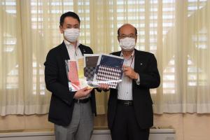 丸山靖雄代表取締役と市長が、色々な種類のマスクケースを持って二人並んで立っている写真
