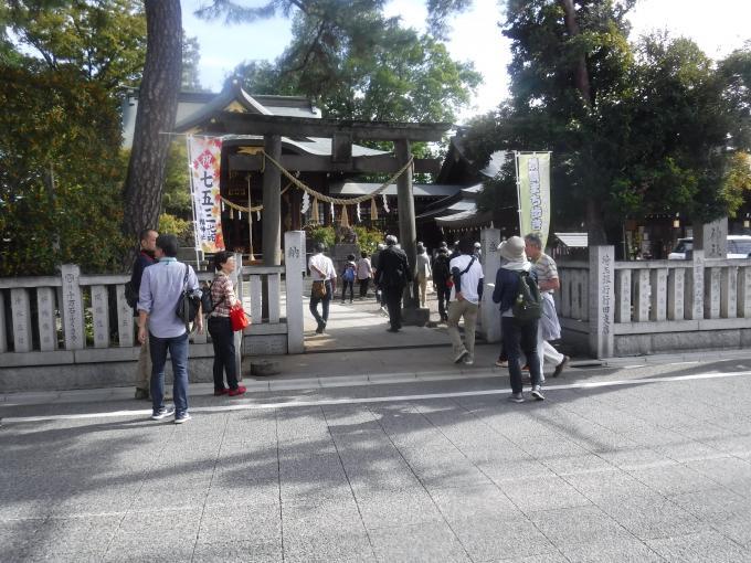 「景観まち歩き」参加者が大きな緑の木々に石の鳥居のある八幡神社に訪れている様子の写真