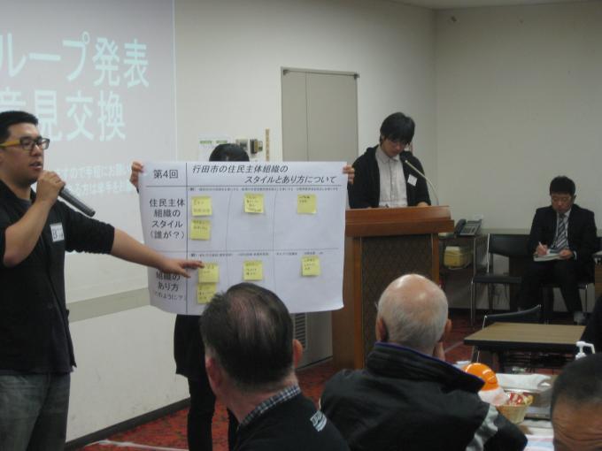 平成27年に行われた「行田市の住民主体組織のスタイルとあり方について」の表を掲げながら男性が発表している写真
