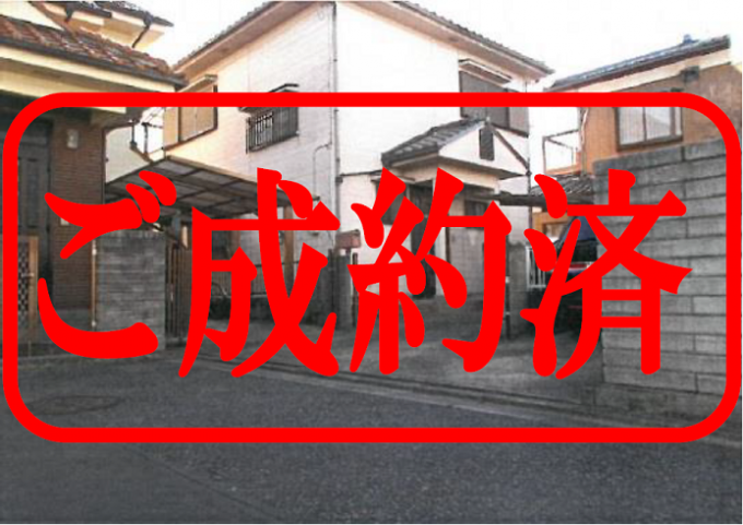 赤文字で「ご成約済」と書いてある、両隣に家が建っている白壁の2階建ての住宅の写真