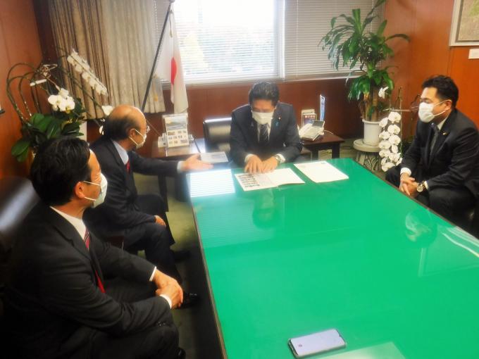 岩井副大臣、石井市長、梁瀬議長、野中代議士が同じテーブルに座り、石井市長が岩井副大臣へ要望内容の説明をしている写真