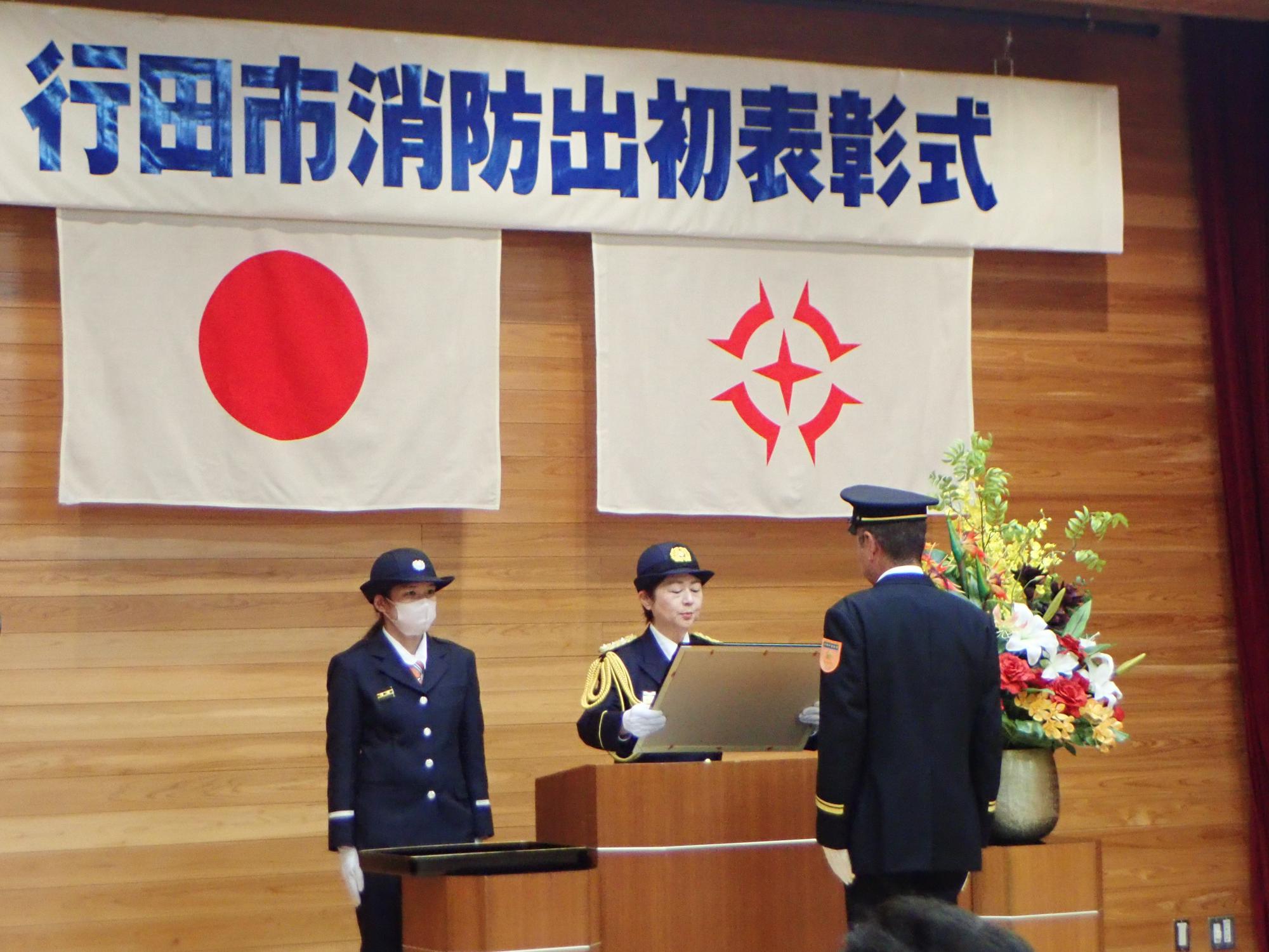 表彰式にて壇上で表彰状を渡している写真