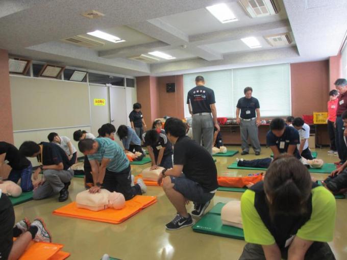 訓練用のマネキンを使って心臓マッサージの実技講習を行っている参加者の写真