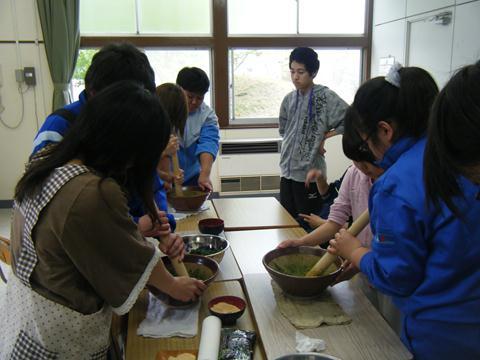 生徒達がすり鉢に入った材料をすりこ木ですりつぶして調理実習をしている様子の写真
