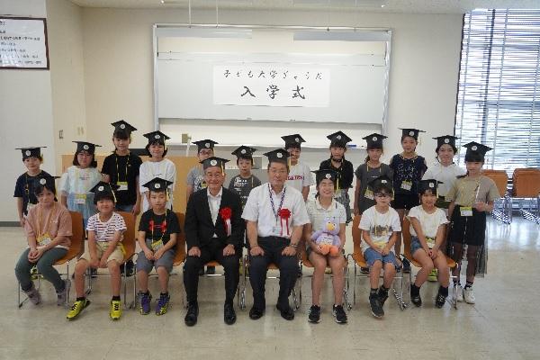 ものつくり大学の赤松学長、齋藤教育長と一緒に撮った18名の児童の集合写真