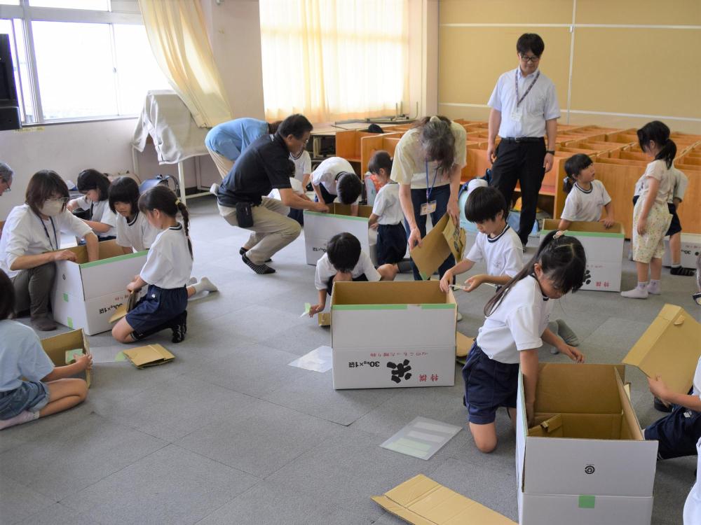 ベッドや机にする段ボールを組み立てる小学生