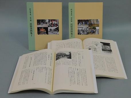 行田市史 資料編 民俗資料集1と民俗資料集2の本が表紙を見せて立てて置いてある、その前に見開きになっている民俗資料集1と民俗資料集2が置いてある写真