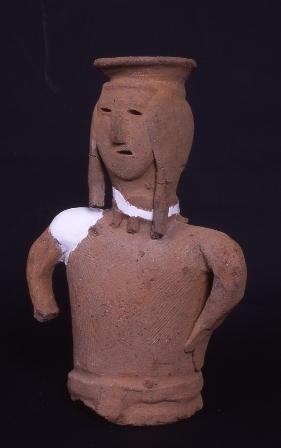 肩の部分が一部白い粘土で修復されており、帽子のような物を頭に着けている上半身だけの埴輪の写真