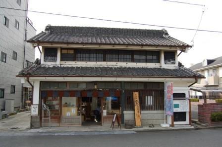 漆喰の白壁、2階建ての古い建物で、1階部分が店舗になっている旧小川忠次郎商店店舗の外観写真