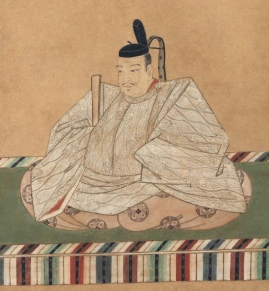 白色の衣服と黒色の冠を頭に被り、笏を右手に持って座っている正装した徳川家康を拡大して写している写真