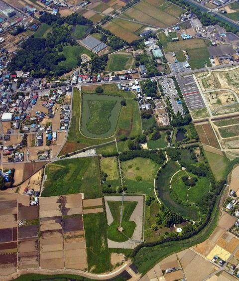 田畑や住宅の一角にある複数の前方後円墳や円墳からなる埼玉古墳群を上空から撮影した写真