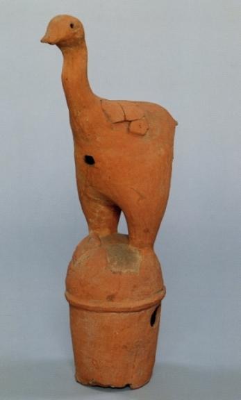 首を上方に伸ばし、2本足で立っている赤茶色の水鳥埴輪の写真