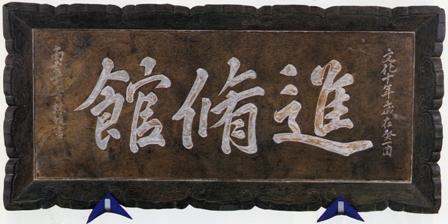 焦げ茶色の木枠で「進脩館」の文字が書かれている藩学進脩館横額の写真