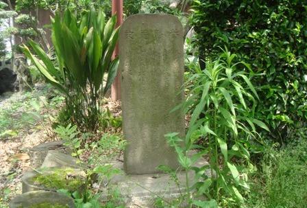 石台の上に置かれた長方形の付紫藤庵記碑の周囲に草や緑の植物が生えている写真
