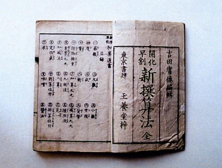 見開きページの右側に大きな文字で「開化早割新撰算法」、左側には文章が書かれている冊子の写真