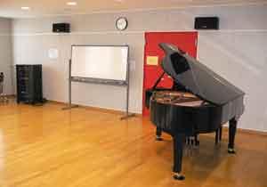 ホワイトボードやグランドピアノが置かれている音楽室の写真